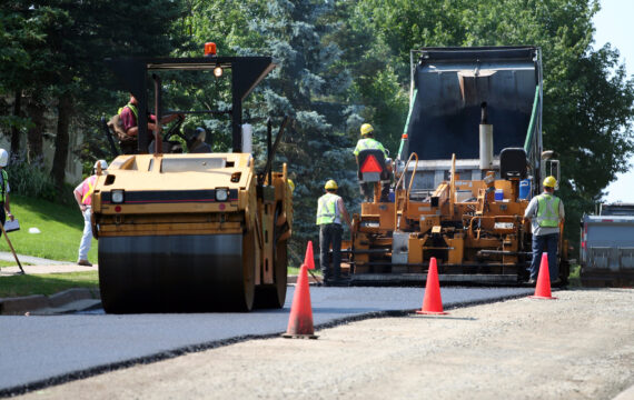An asphalt spreader is used to place the first layer of asphalt on a city street renewal project.