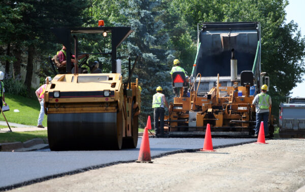 An asphalt spreader is used to place the first layer of asphalt on a city street renewal project.