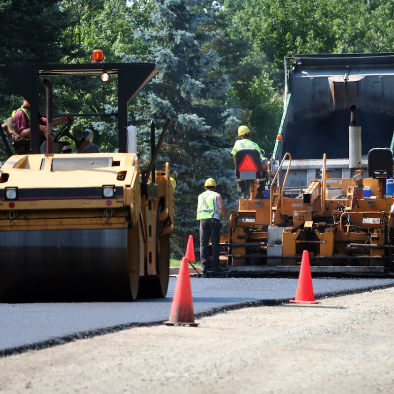 An asphalt spreader is used to place the first layer of asphalt on a city street renewal project.